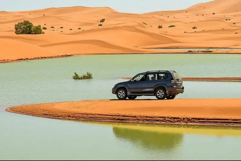 4x4 vehicle beside a water-filled oasis in the Merzouga desert