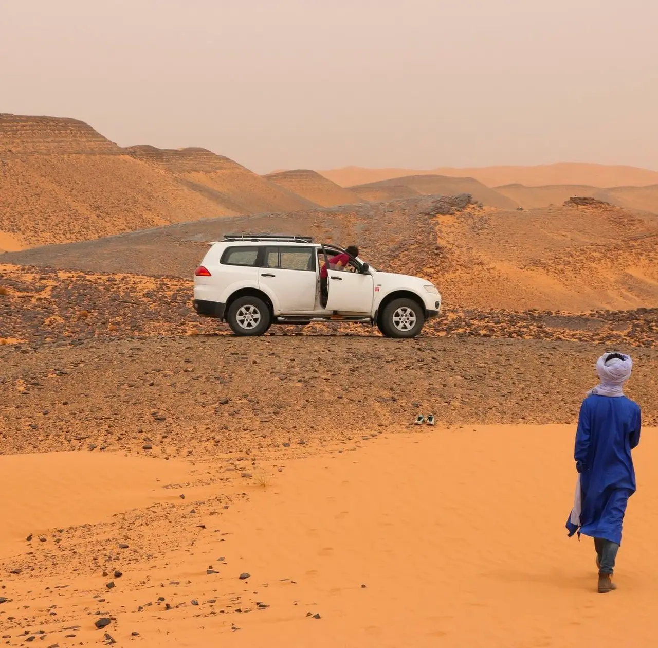 4x4 trip across the Merzouga desert, with the guide looking out over the dunes