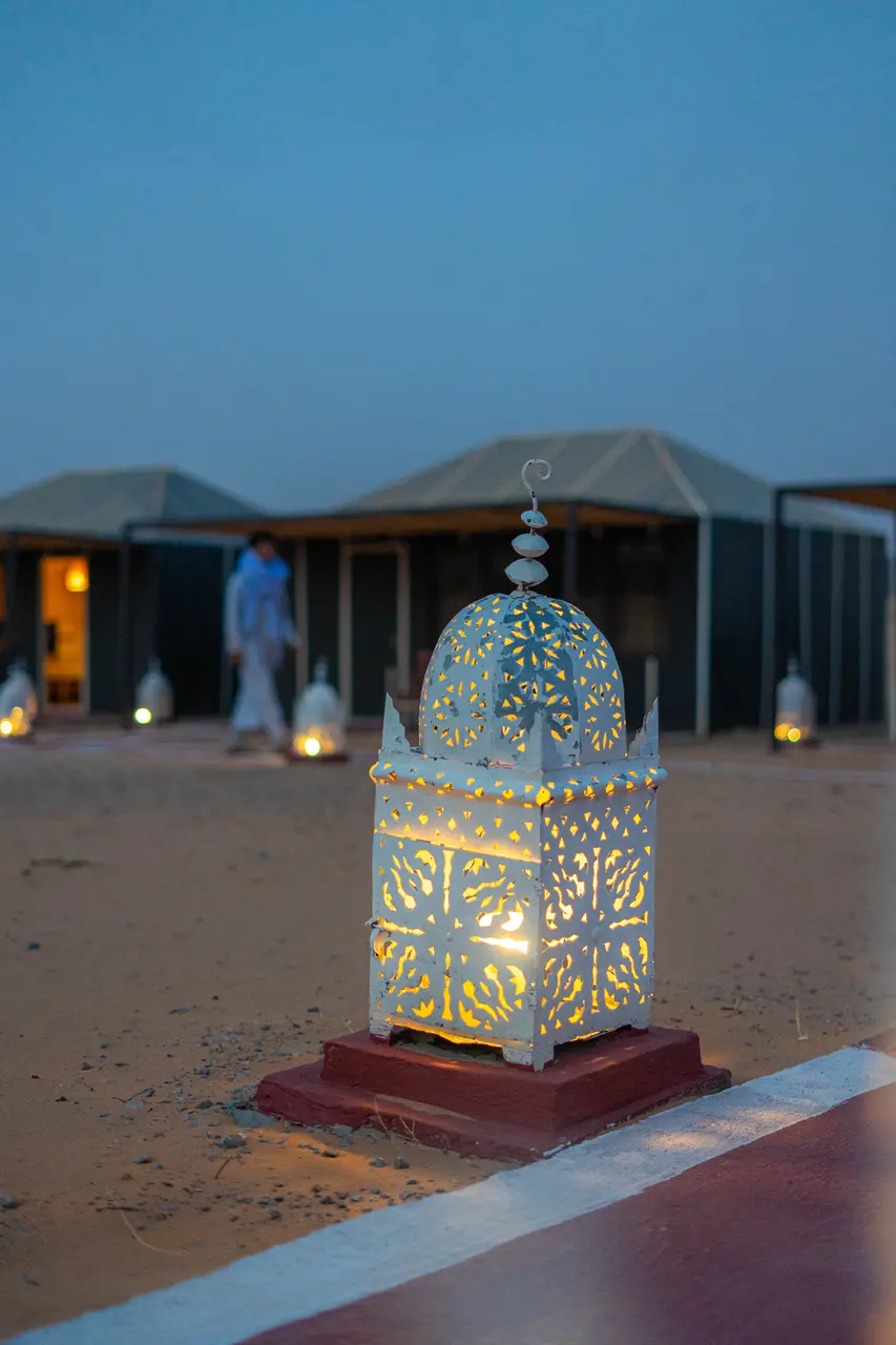 Moroccan lantern lit, marking the path between the tents at the camp