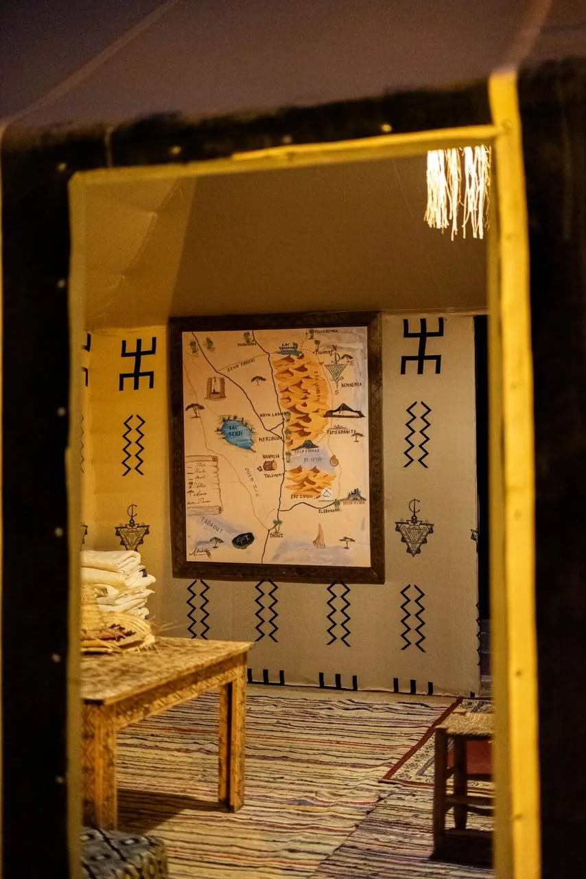 Berber tent interior with a painted desert map and handmade rugs