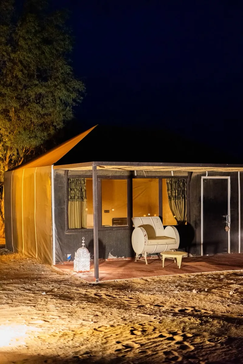 Luxury tent lit at night with a private terrace and outdoor sofa