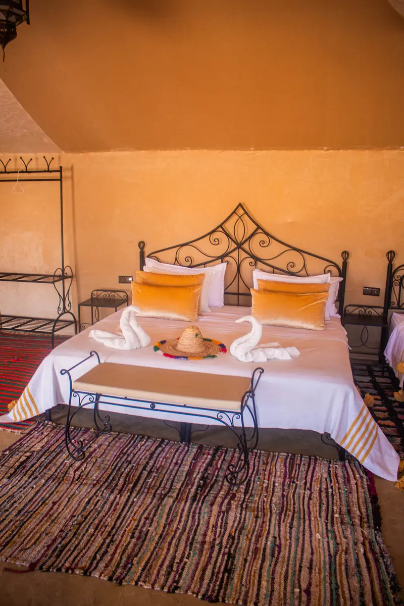 Double tent with a large bed and wrought-iron headboard, ready for arrival