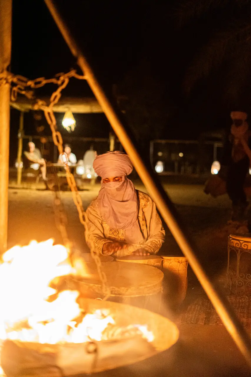 Musicien berbère en turban jouant près du feu au campement Tassili