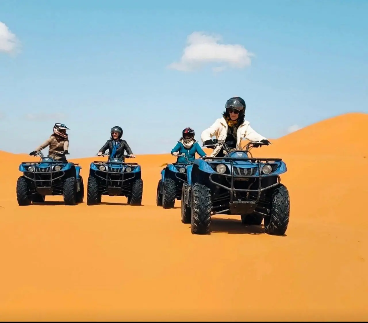Quatre personnes en quad sur les dunes de sable du désert de Merzouga